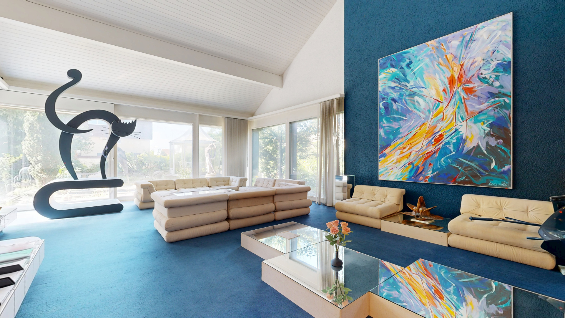 Luxuriöses Wohnzimmer mit hellem Sofa, blauem Teppich und farbenfrohem Kunstwerk